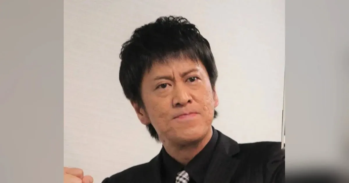 お笑いコンビ『ブラックマヨネーズ』の吉田敬さんを思わせる、スーツ姿でカメラを見つめる男性のイメージ写真
